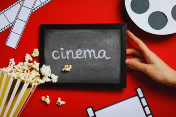 lavagnetta con scritto cinema, pop corn e mano