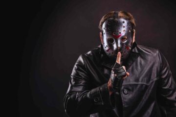 Serial killer che fa il gesto del silenzio con il dito, sul viso la maschera di Venerdi' 13