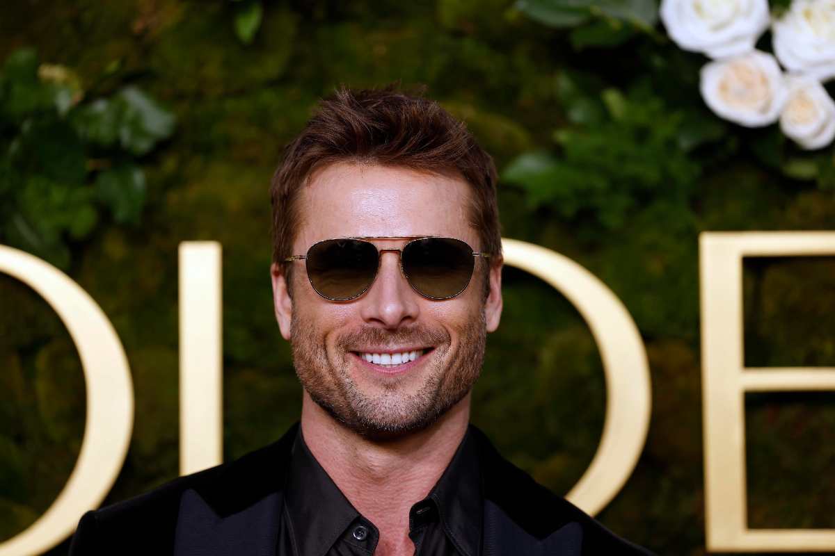 Glen Powell sorridente con gli occhiali da sole