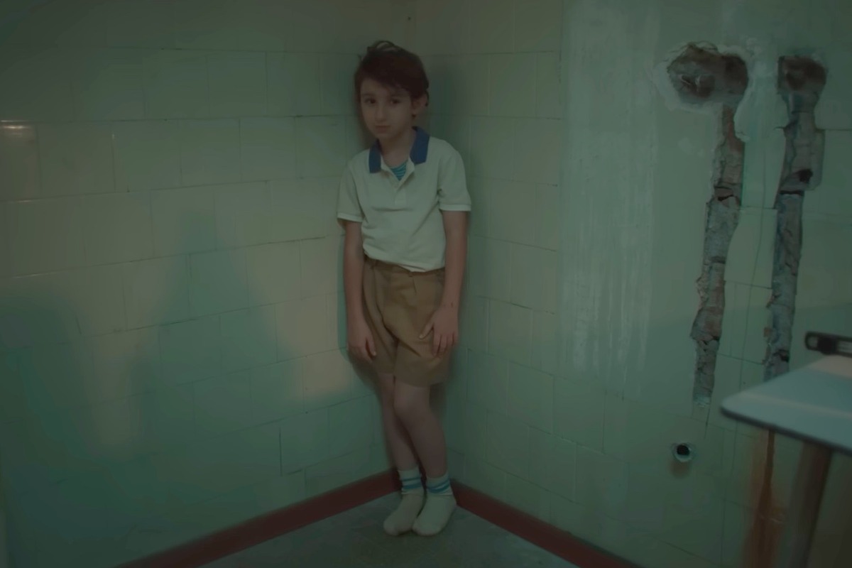 Un bambino appoggiato a un angolo del muro