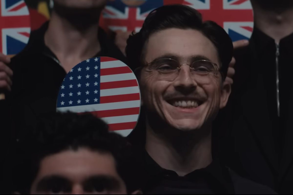 Timothée Chalamet con in mano la bandierina americana in una scena di Marty Supreme