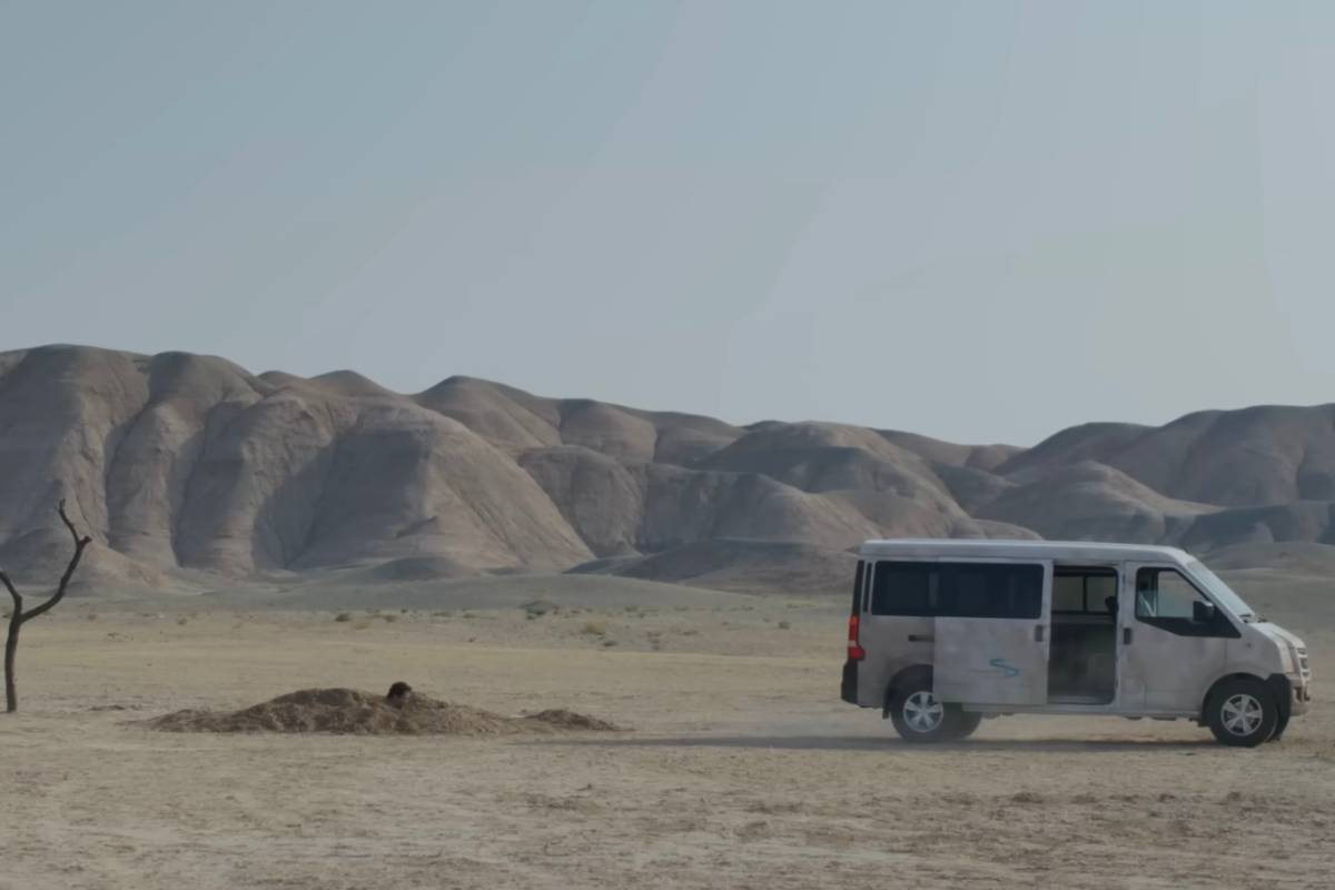 Un camioncino nel deserto con un uomo che scava una buca